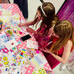two girls in pink dresses at an activities table